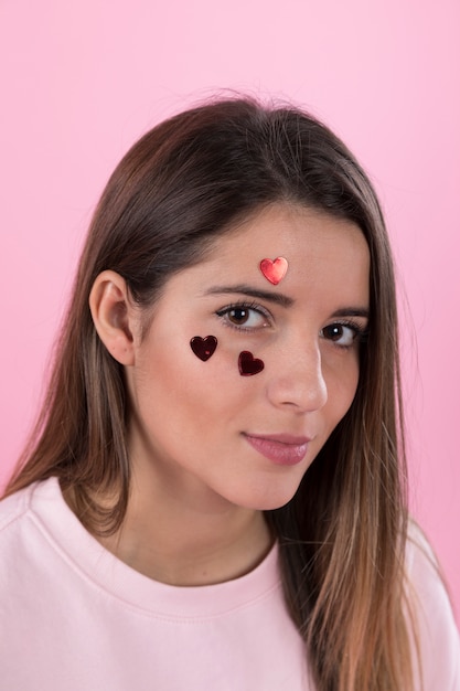 Mujer joven con adornos de corazones en la cara