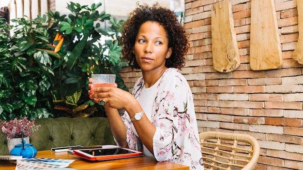 Una mujer joven africana bebiendo un cóctel en el restaurante