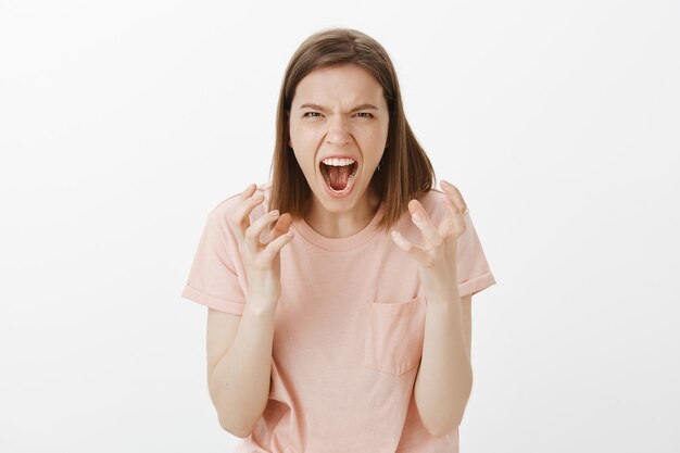Mujer joven agresiva y cabreada gritando de odio, enojada con alguien