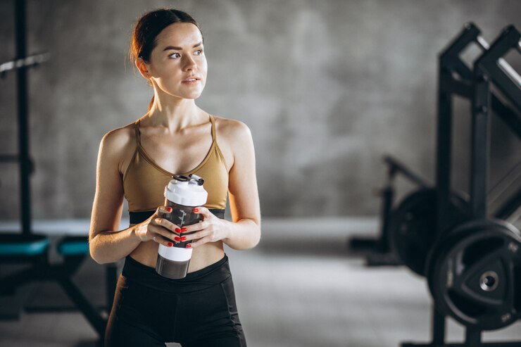 Foto gratuito mujer joven agua potable después de hacer ejercicio en el gimnasio.