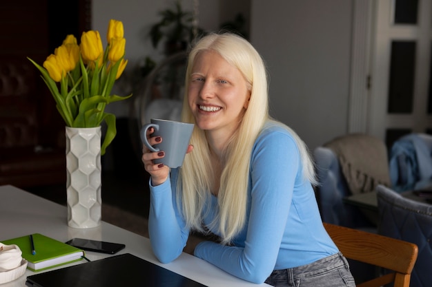 Mujer joven con albinismo y taza de café en la cocina