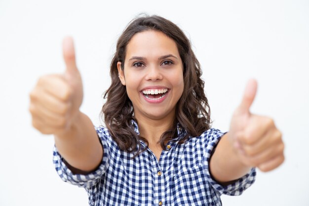 Mujer joven alegre que muestra los pulgares para arriba