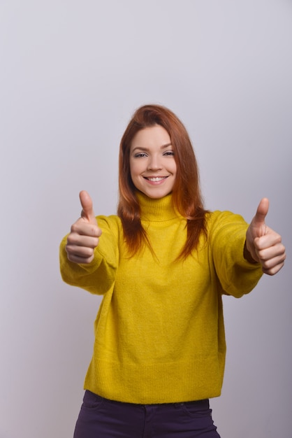 Foto gratuita mujer joven alegre que muestra los pulgares para arriba