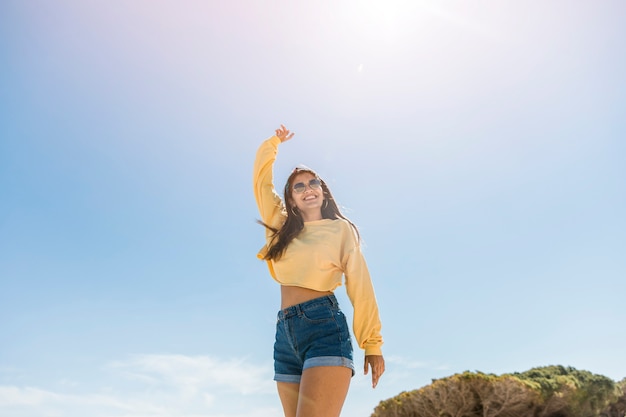 Mujer joven alegre que se relaja en luz del sol del verano