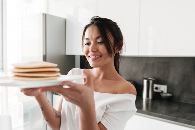 Mujer joven alegre que sostiene los panqueques.