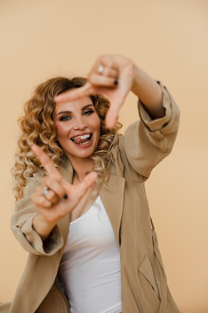 Mujer joven alegre sonriendo y haciendo un marco con sus dedos. Concepto de moda