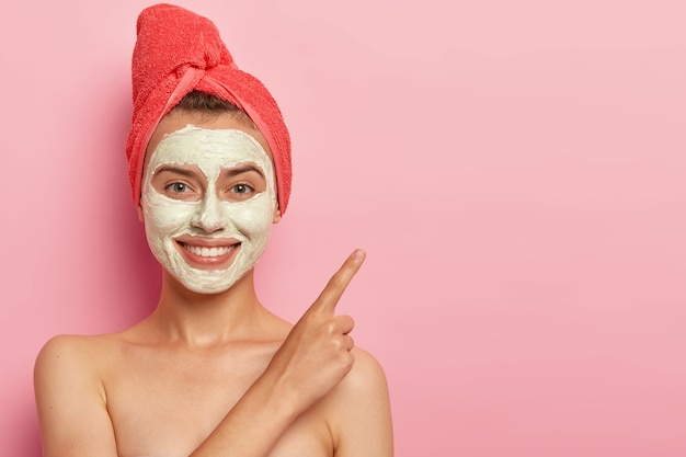 Mujer joven alegre con suave sonrisa, señala el dedo índice