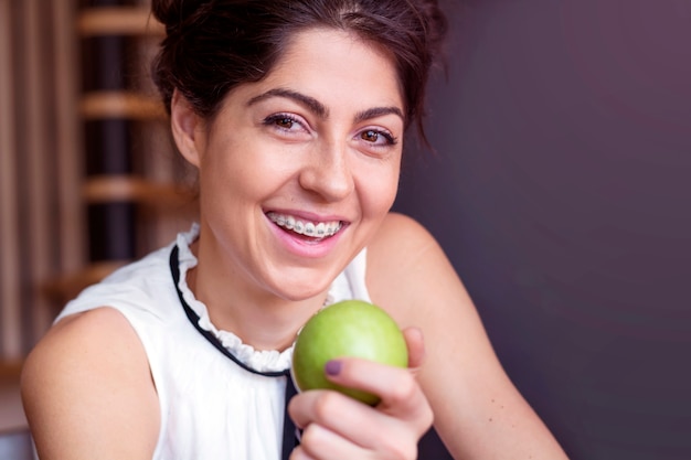 Mujer joven alegre sujetando una manzana