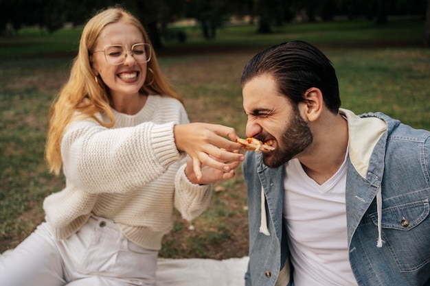 Mujer joven alimentando pizza a su novio