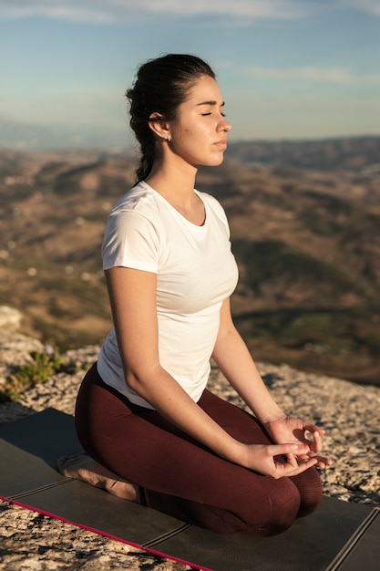 Foto gratuita mujer joven de alto ángulo en estera meditando