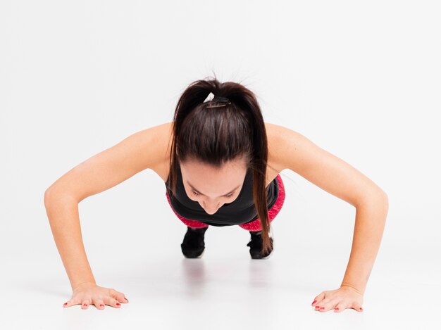 Mujer joven de alto ángulo haciendo flexiones