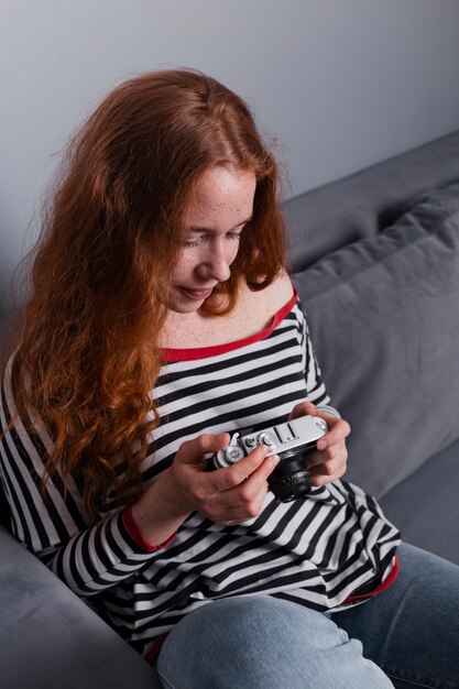 Mujer joven de alto ángulo revisando fotos en la cámara