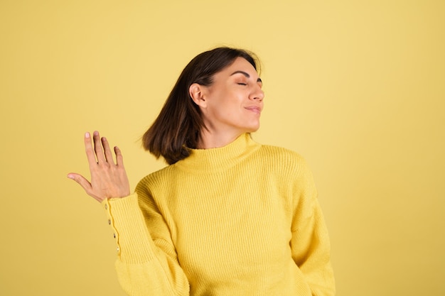 Foto gratuita mujer joven, en, amarillo, cálido, suéter, con, ojos cerrados