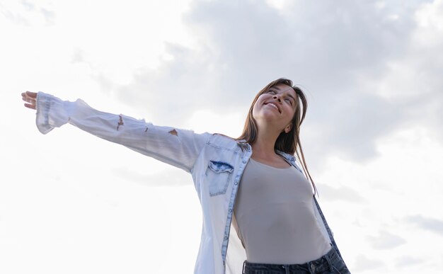 Mujer joven de ángulo bajo sonriendo afuera