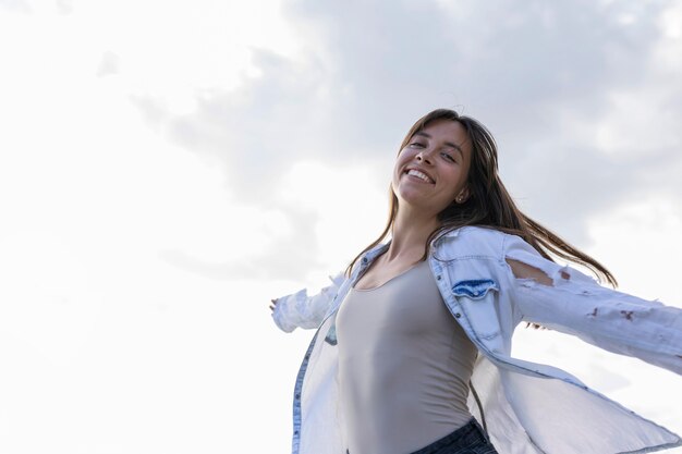 Mujer joven de ángulo bajo sonriendo al aire libre