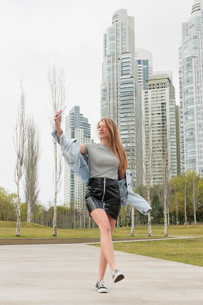 Foto gratuita mujer joven de ángulo bajo tomando selfie