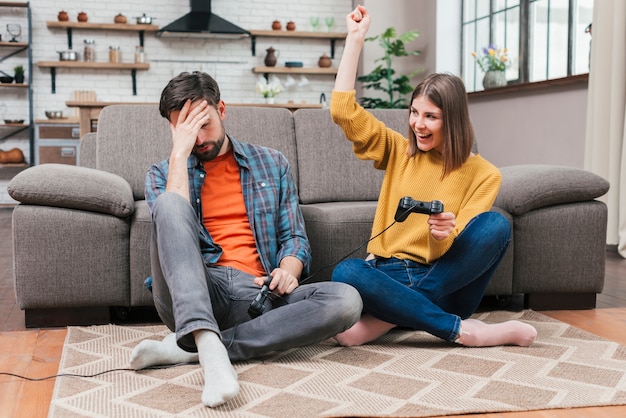 Mujer joven animando después de ganar el videojuego con su esposo