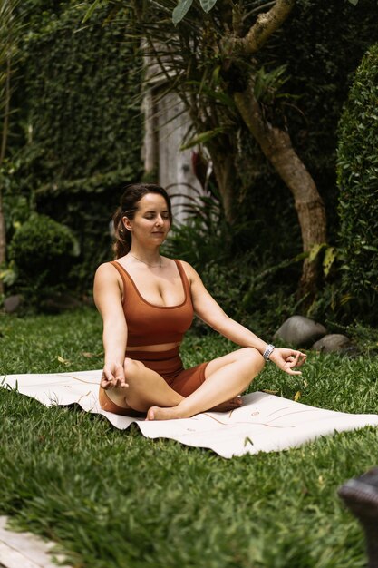 Mujer joven con apariencia corporal positiva practicando yoga sola en la terraza junto a la piscina en la isla tropical de Bali, Indonesia. Deporte, fitness, concepto de estilo de vida saludable.