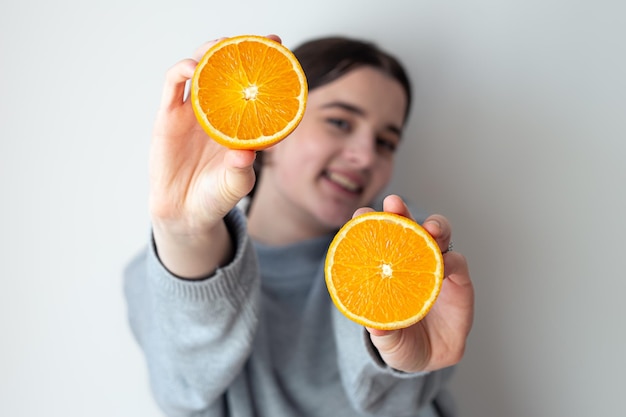 Foto gratuita una mujer joven con apetitosas mitades de una naranja sobre un fondo blanco.