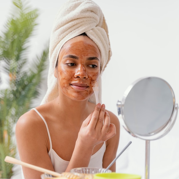 Foto gratuita mujer joven aplicando una mascarilla natural