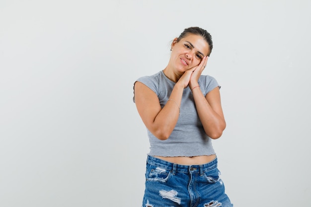 Mujer joven apoyado en las palmas de las manos como almohada en camiseta, pantalones cortos y aspecto lindo