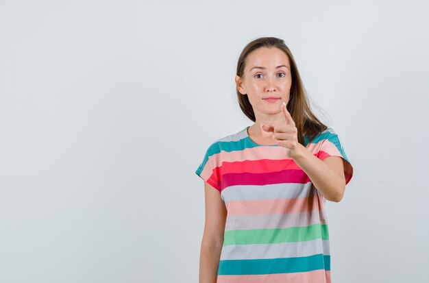 Mujer joven apuntando al frente para advertir en la vista frontal de la camiseta.