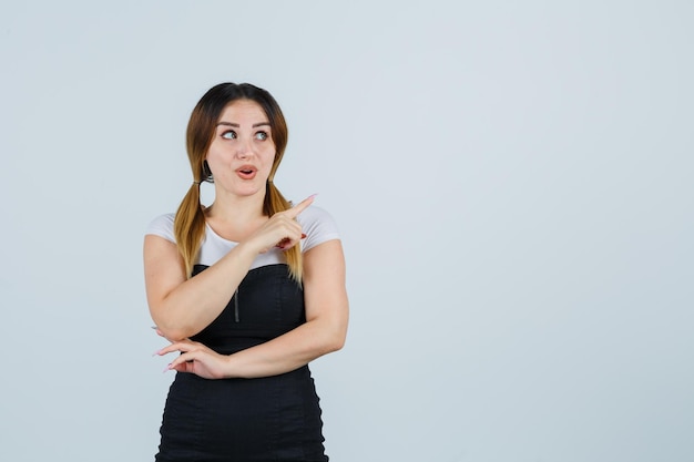 Mujer joven apuntando a la esquina superior derecha