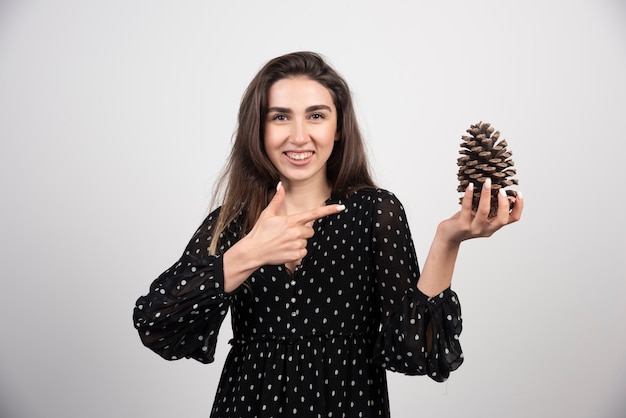 Mujer joven apuntando a una gran piña