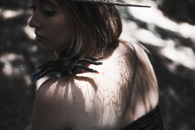 Mujer joven con araña en el hombro en el bosque