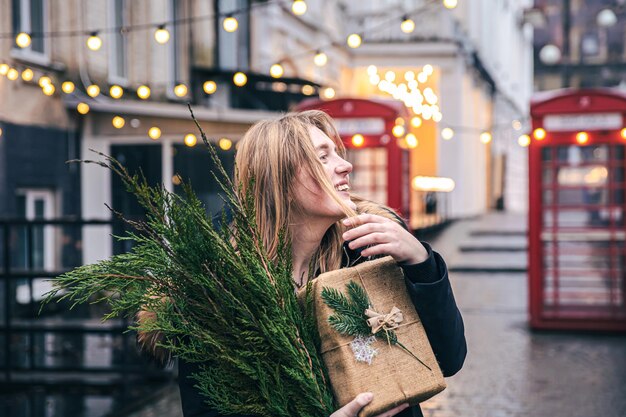 Mujer joven con un árbol de Navidad y una caja de regalo sobre un fondo borroso