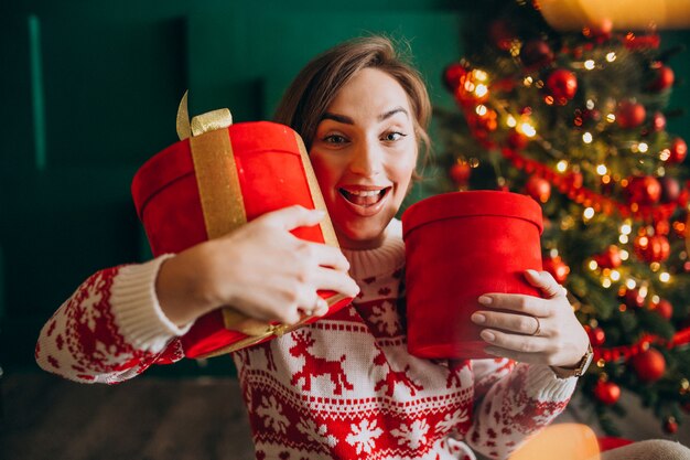 Mujer joven con árbol de Navidad con cajas rojas