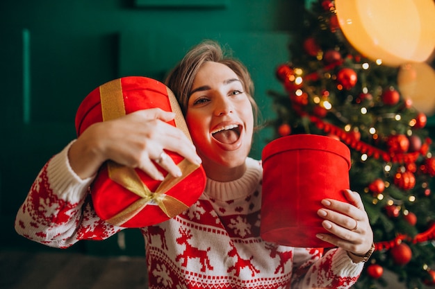 Mujer joven con árbol de Navidad con cajas rojas