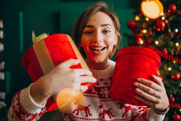 Mujer joven con árbol de Navidad con cajas rojas