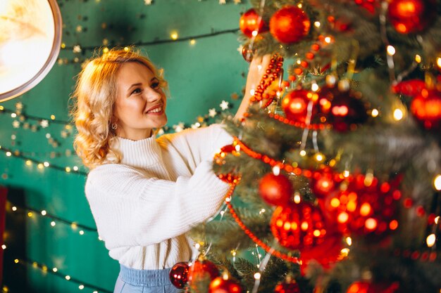 mujer joven por el árbol de navidad en navidad