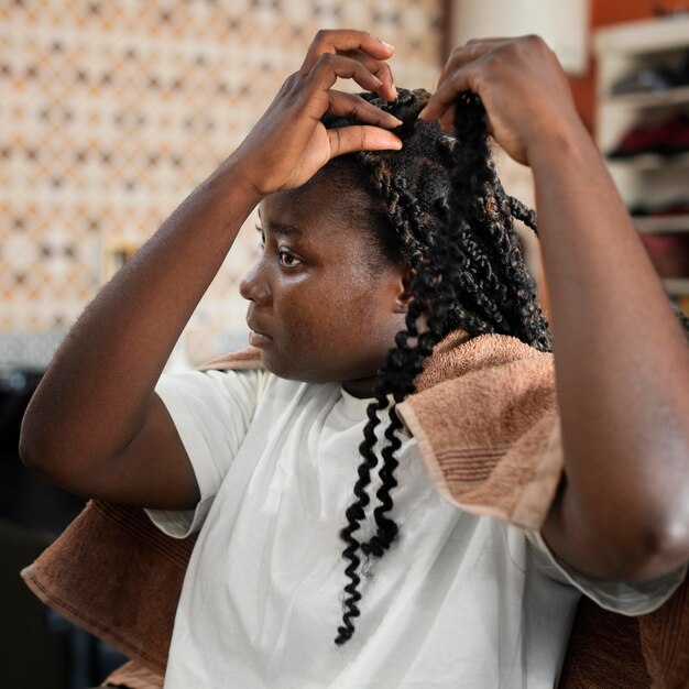 Mujer joven arreglando su cabello en el salón de belleza