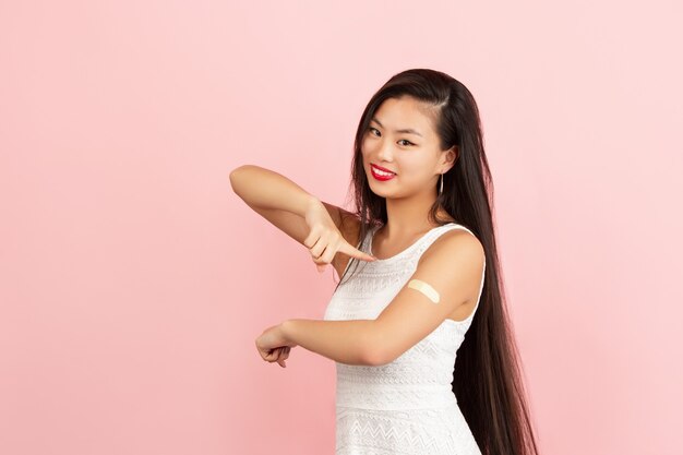 Mujer joven asiática apuntando el yeso de la etiqueta engomada