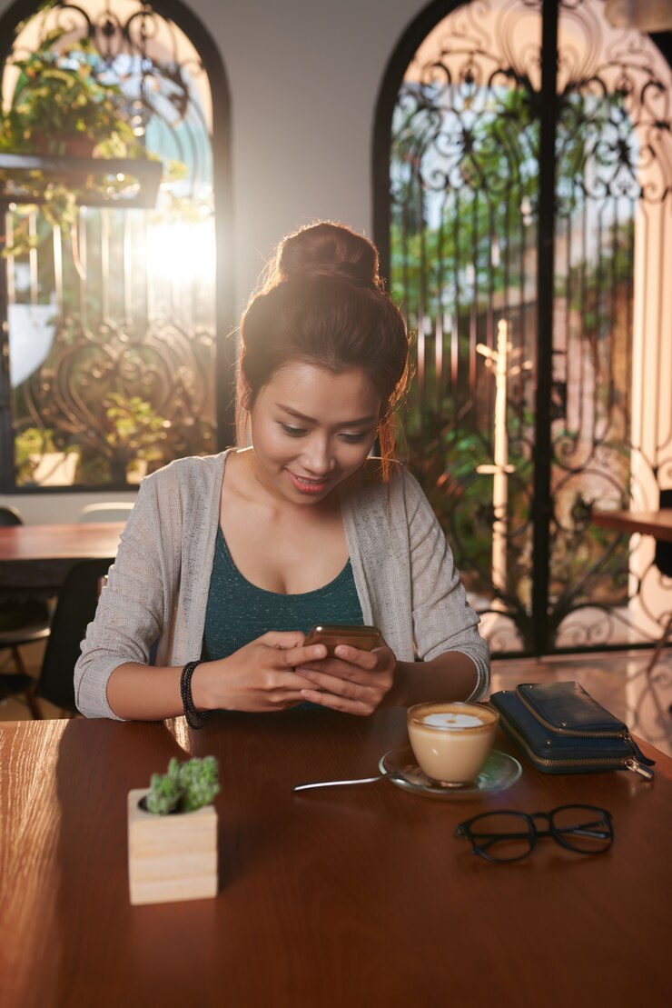 Foto gratuito mujer joven asiática enviando mensajes de texto en café