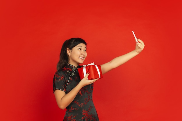 Mujer joven asiática tomando selfie con presente para feliz año nuevo chino