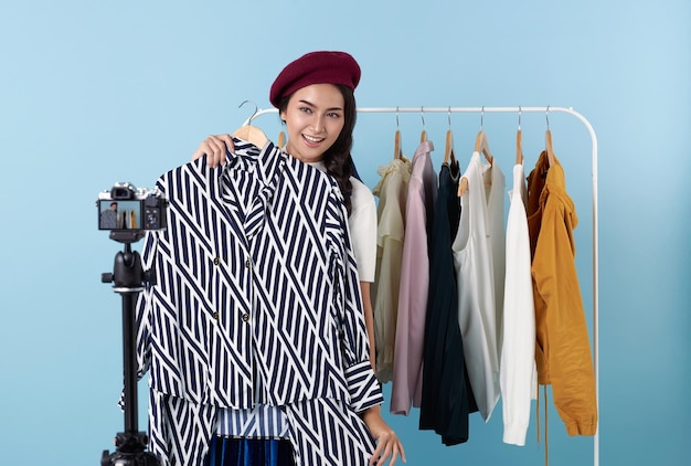 Mujer joven asiática en vivo mostrando ropa frente a la cámara para la venta de ropa de moda