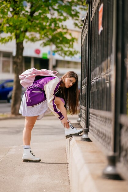 Mujer joven atando los cordones de sus zapatos en sus botas blancas