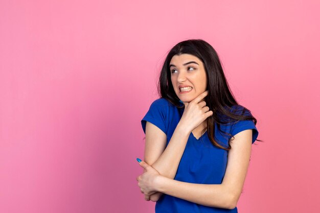 Mujer joven aterrorizada de pie sobre fondo rosa