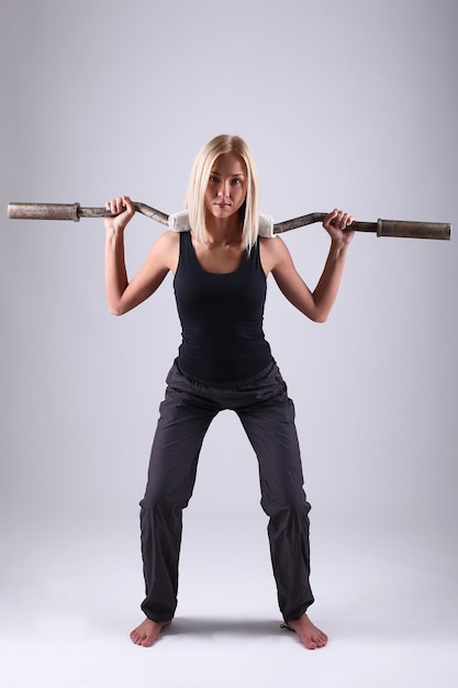 Mujer joven atleta con barra de ejercicio