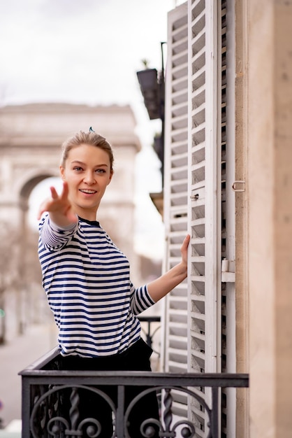 Mujer joven atractiva en el balcón por la mañana en la ciudad de París. vista del arco triunfal.