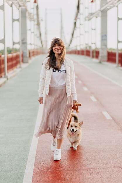 Mujer joven atractiva caminar corgi al aire libre