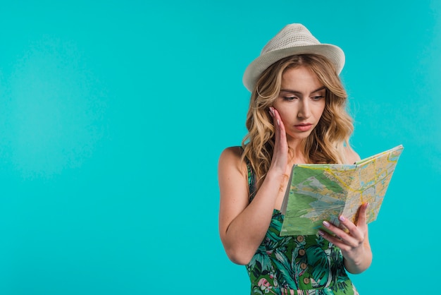 Foto gratuita mujer joven atractiva concentrada en el sombrero y el vestido que miran el mapa