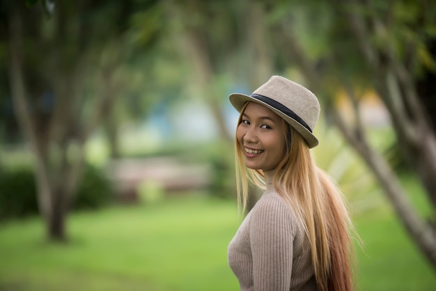 Mujer joven atractiva que disfruta de su tiempo afuera en parque con el fondo del parque de naturaleza.