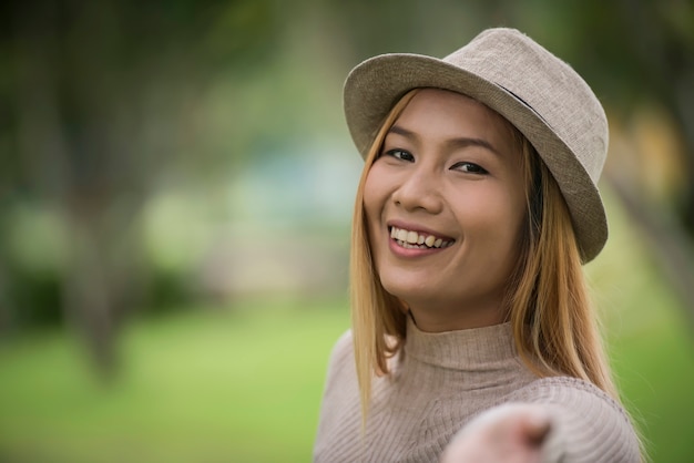 Mujer joven atractiva que disfruta de su tiempo afuera en parque con el fondo del parque de naturaleza.