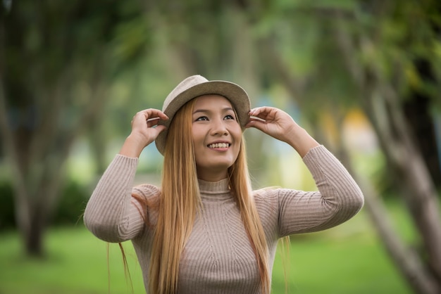 Mujer joven atractiva que disfruta de su tiempo afuera en parque con el fondo del parque de naturaleza.