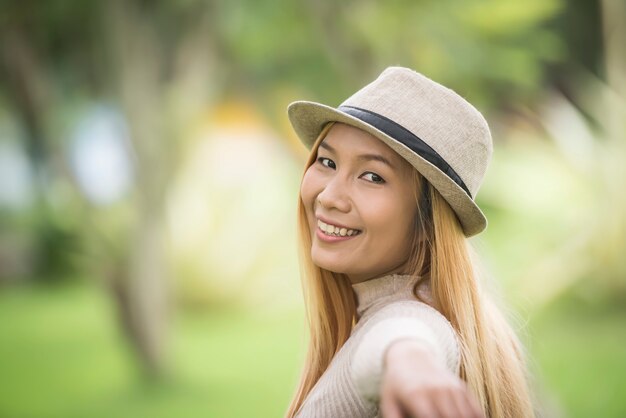 Mujer joven atractiva que disfruta de su tiempo afuera en parque con el fondo del parque de naturaleza.
