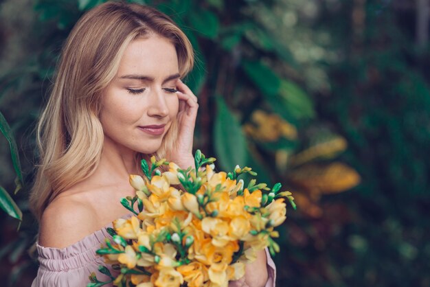 Mujer joven atractiva que sostiene las flores frescas amarillas